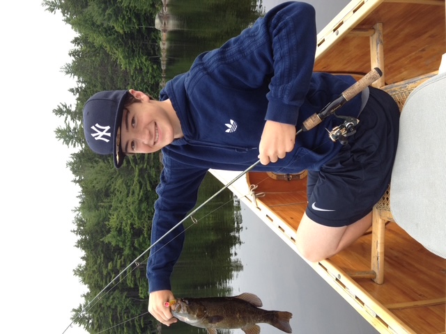 Angler holding a chain pickerel from a canoe