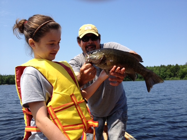 Angler with a smallmouth bass lakeside