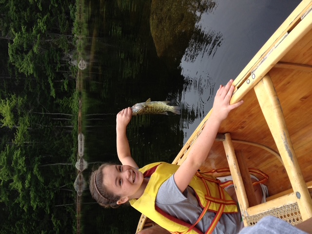 Young angler with a smallmouth bass in a Grand Laker canoe